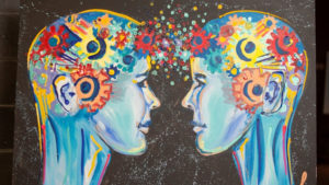 A painting of two people facing each other in profile; both are painted in an impressionist style, in hues of blue. Their heads are full of colourful gears, which spill out and meet in the space between them.