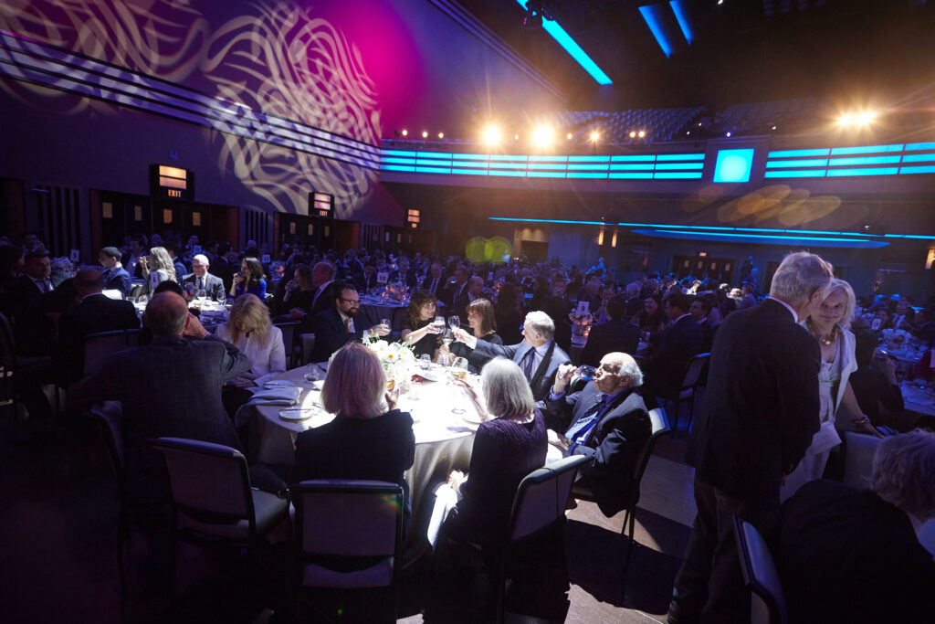 The dining hall at the Carlu, well dressed guests sit around a table